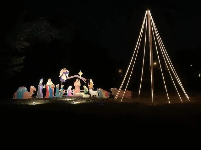 A lighted nativity scene and a tree of string lights at night